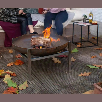 Rustic moodz classic fire bowl in corten steel with circular bowl and sturdy legs featuring active flame over logs