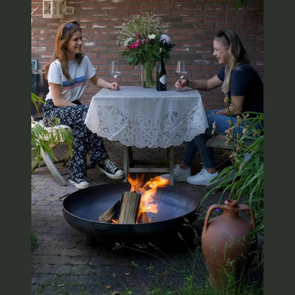 Black round fire pit with burning wood and flames from moodz feet and handle fire bowls in corten and stainless steel