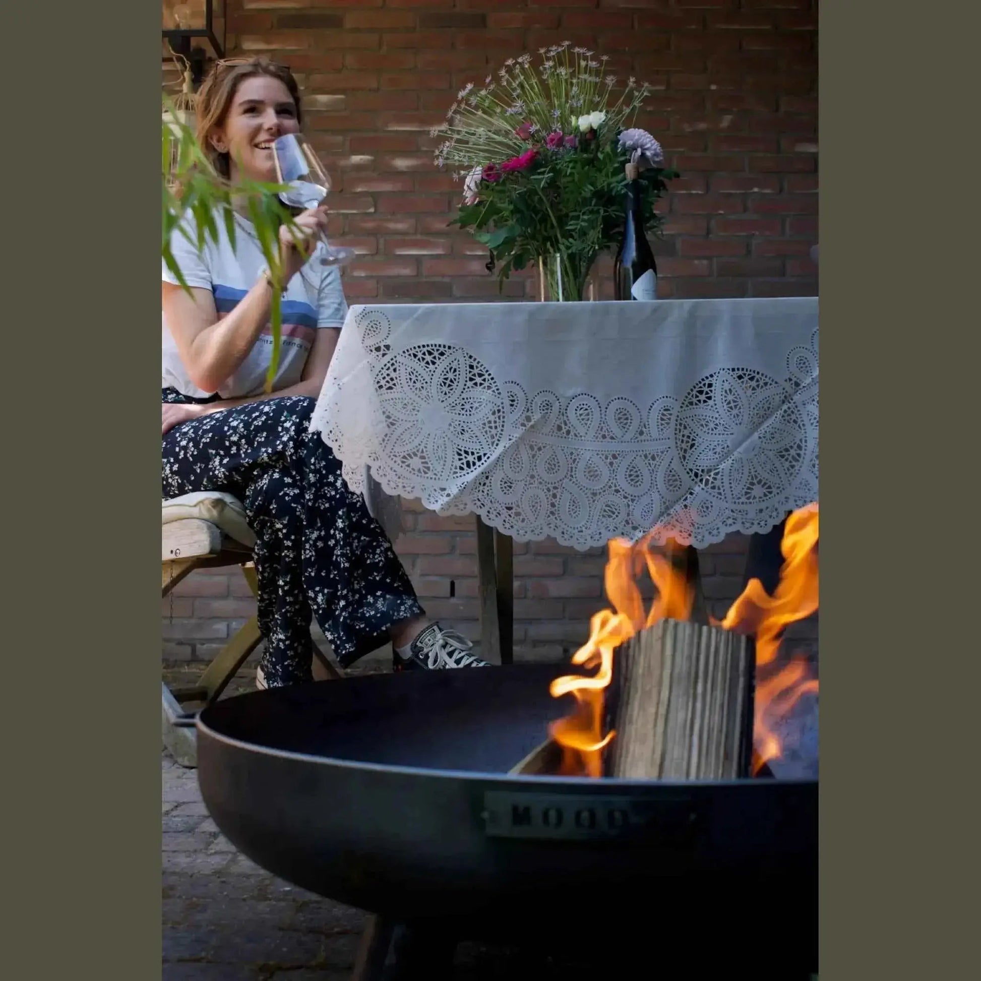 Black metal moodz feet and handle fire bowl with flames burning inside made of corten and stainless steel