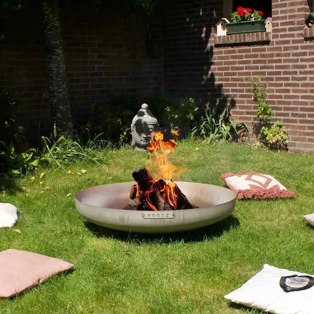 A sleek modern stainless steel fire bowl moodz with minimalist design and woodz branding engraved on the rim