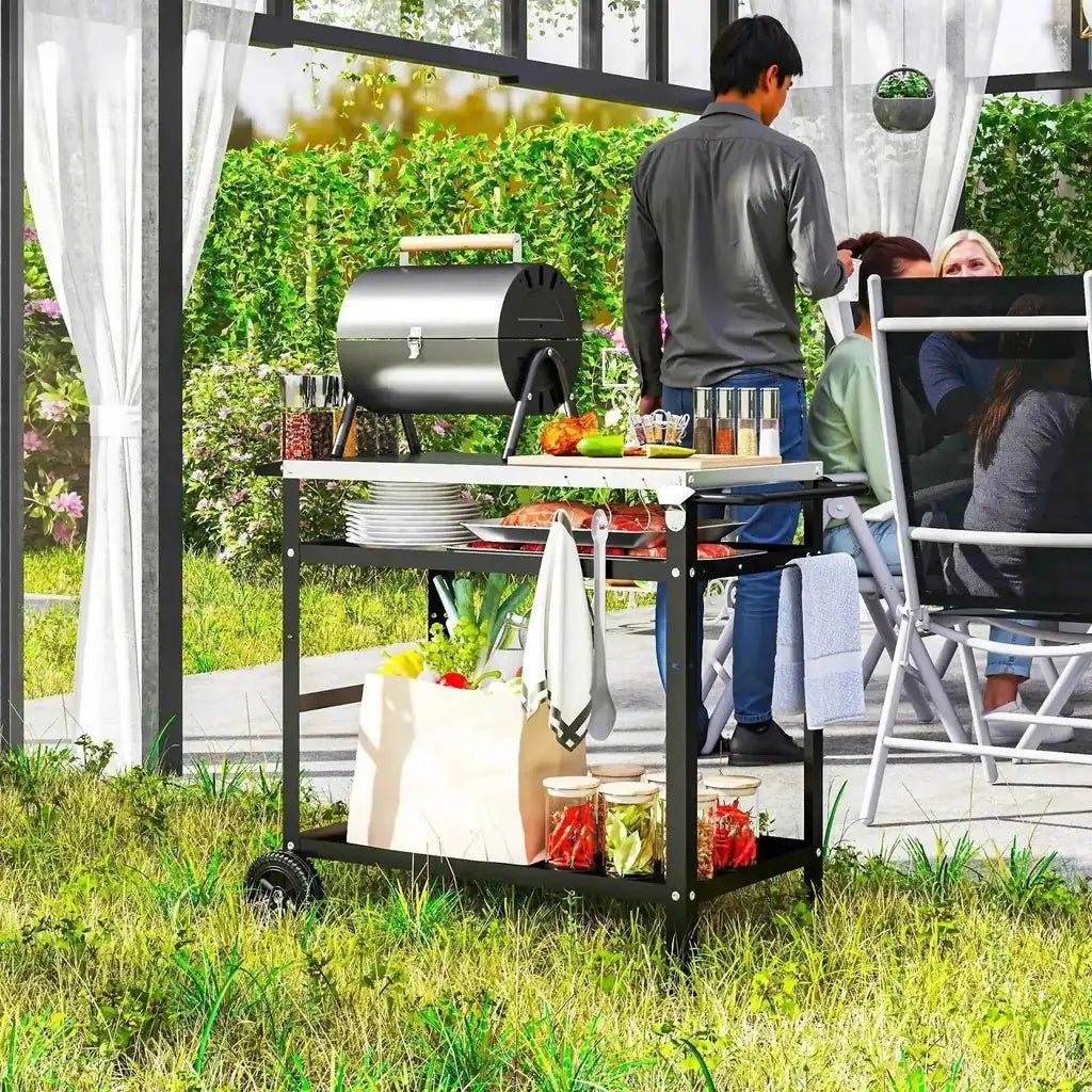 Black metal patio grill cart with stainless steel top and adjustable shelf holding jars plates and towels outdoors