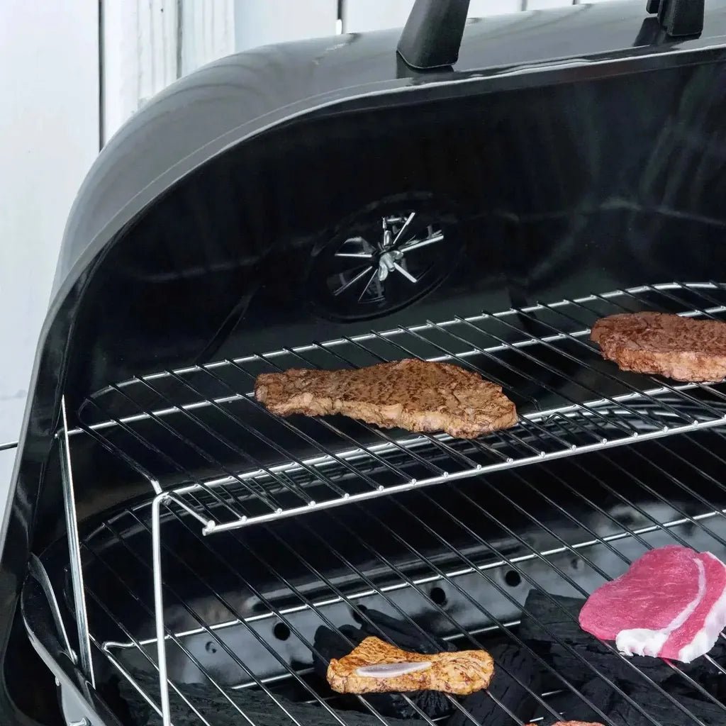 Black charcoal outsunny portable bbq grill with stainless steel racks holding various cuts of meat and wheels