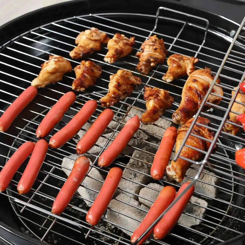 Grilled chicken wings and sausages sizzling on a black Outsunny portable charcoal kettle grill with trolley and metal grates