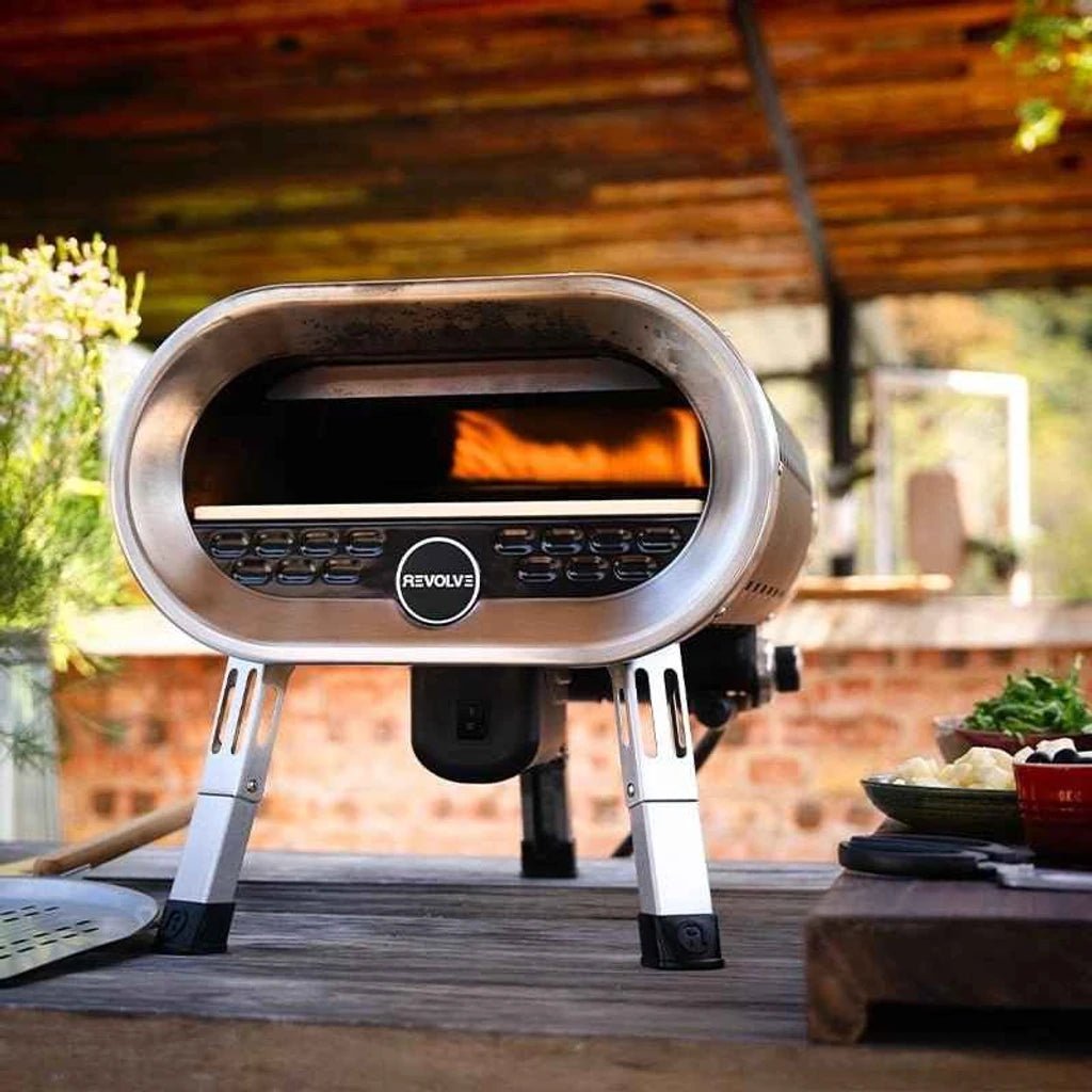 Stainless steel revolve pizza oven with sleek oval design and visible flame gas-fired rotating stone by Revolve