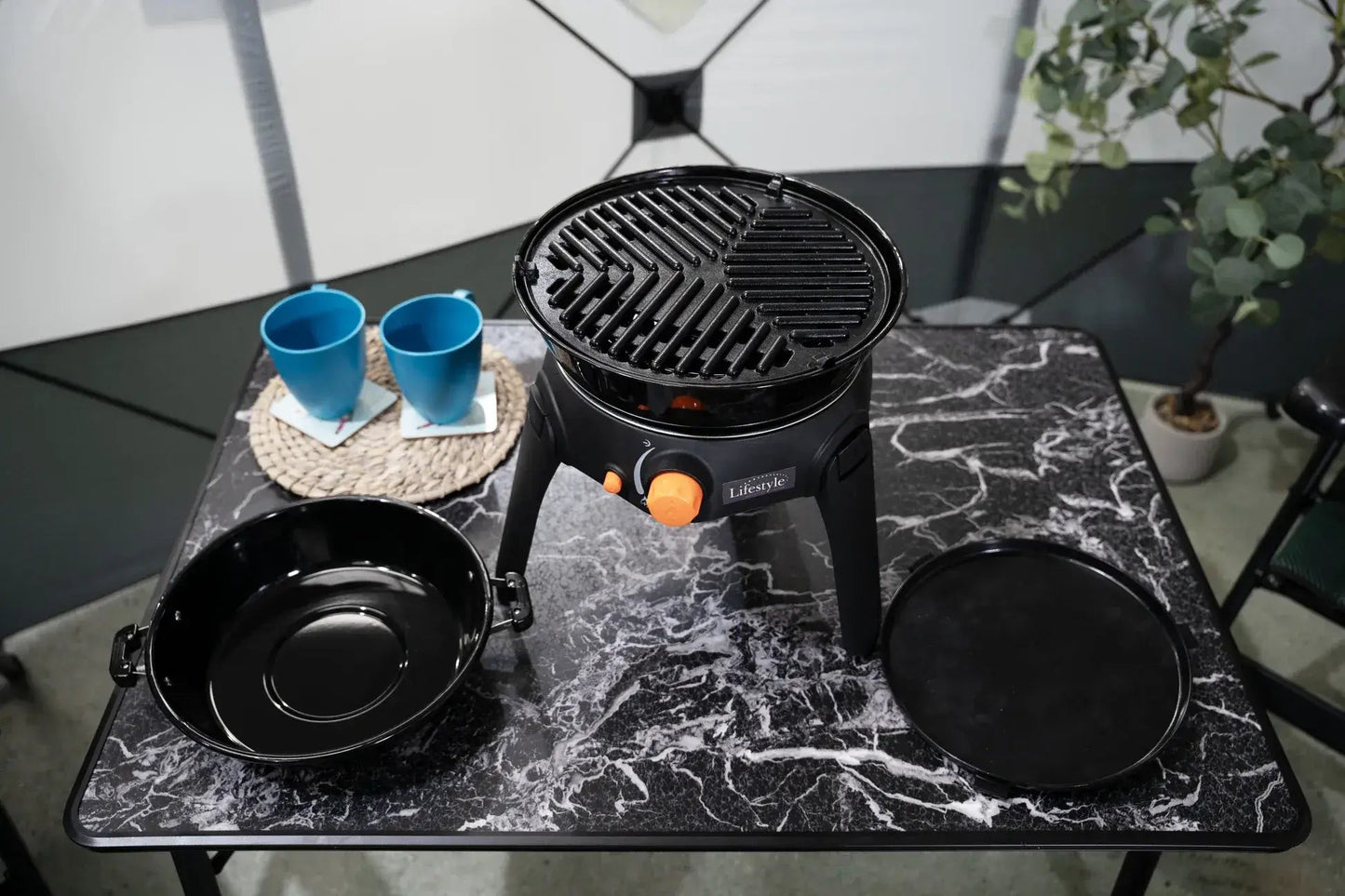 Black portable gas grill with orange control knob and lifestyle branding for outdoor cooking sahara multi grill