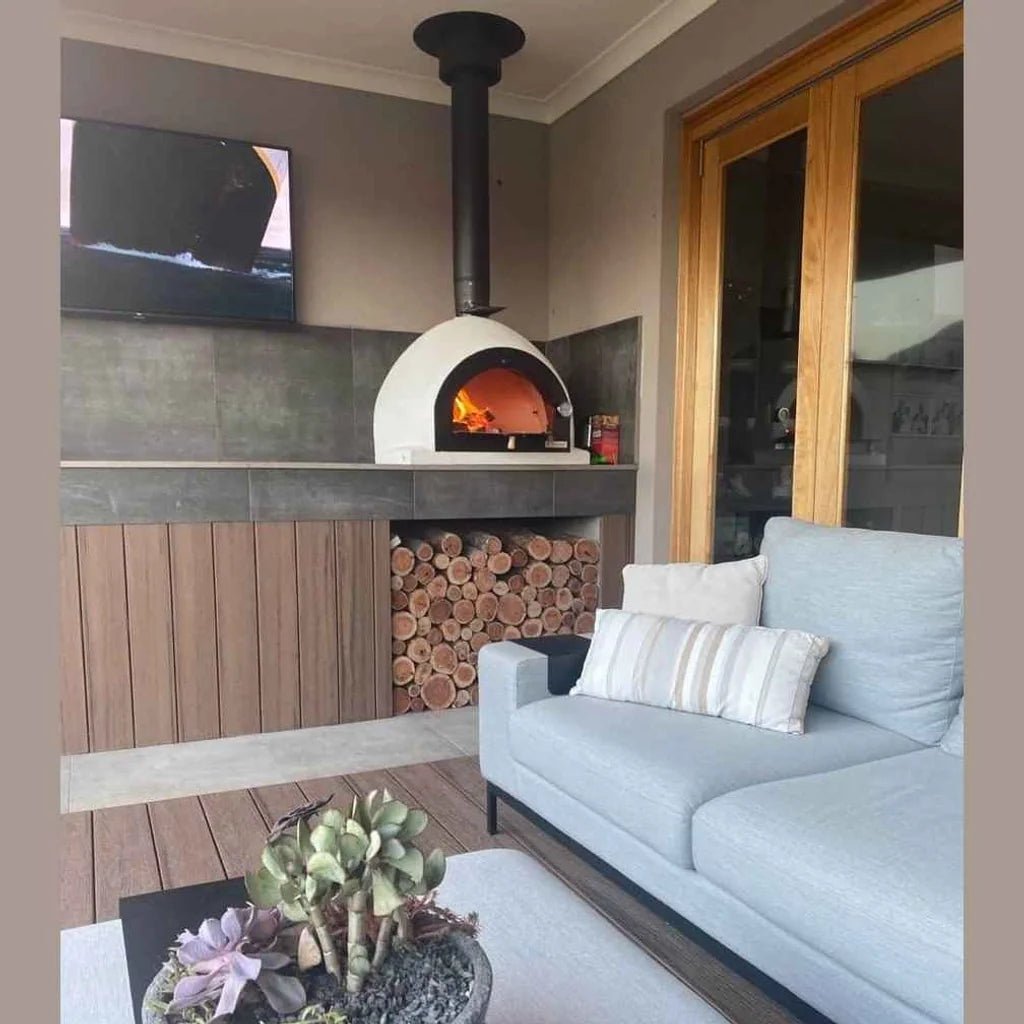 White ceramic xclusiveDecor royal wood fired pizza oven with black chimney and glowing orange fire inside